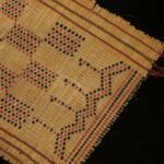 Carpet made of very sturdy herb stems with leather strips that form traditional Tuareg geometric designs. Approx. cm. 79,5 x 40,0 (30.31” x 16.14”).  The Tuareg people inhabit a large area, covering almost all the middle and western Sahara and the north-central Sahel. They are probably descended from the ancient Libyan people of the kingdom of the Garamantes, described by Herodotus. Tuareg are mostly nomads. For over two millennia, the Tuareg operated the trans-Saharan caravan trade connecting the great cities on the southern edge of the Sahara via five desert trade routes to the northern coast of Africa (Mediterranean).  morr23